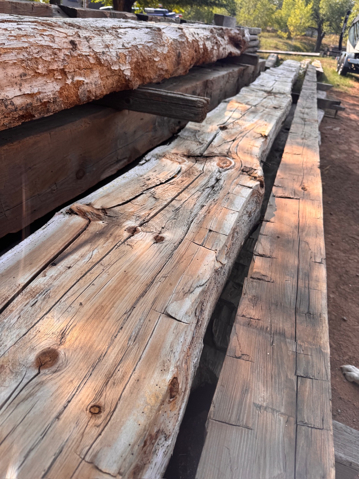 Weathered timber stacked in yard, showing raw reclaimed material texture